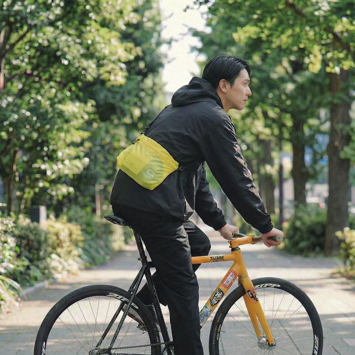 ボディバッグを身につけて自転車に乗る男性